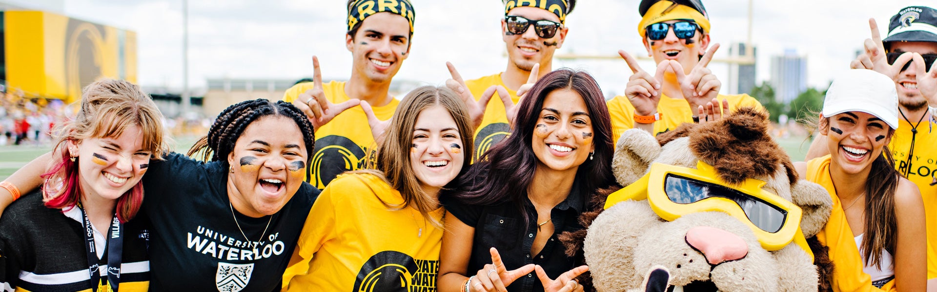 Students in black and gold smile at the camera