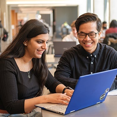 Two students applying to university on a laptop