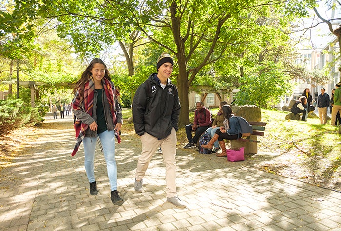 Two students walking and talking on campus in the fall