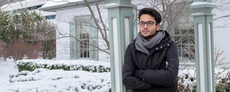 Student leaning against post on a snowy day