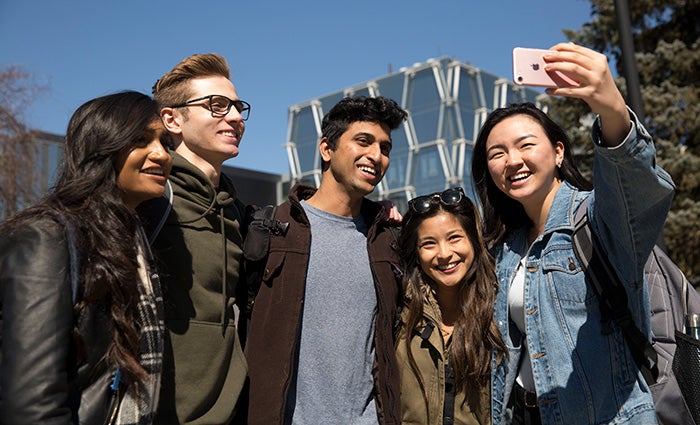 Group of five students taking a photo together