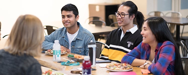 Group of students smiling together around a table