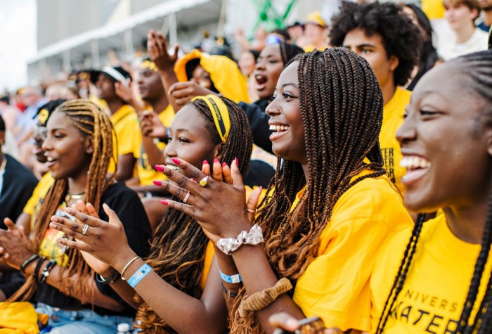 Students cheer and clap on bleachers during Black and Gold day