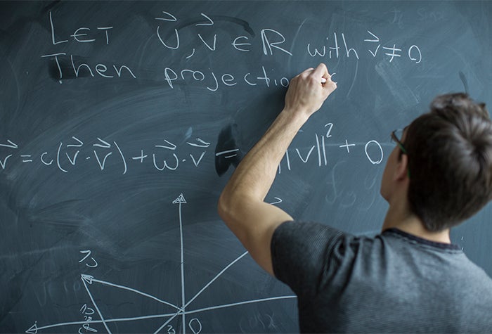 Student solving math equations on a chalkboard