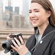 Student with camera standing on Brooklyn Bridge