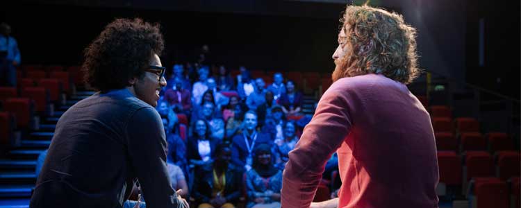 Two Communications students sitting on a stage together