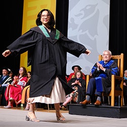 A graduating student walks across the stage at convocation