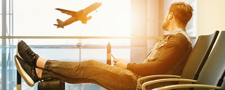 Person lounging on a chair and watching an airplane through a window