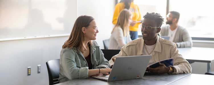 Two students talking in a classroom.