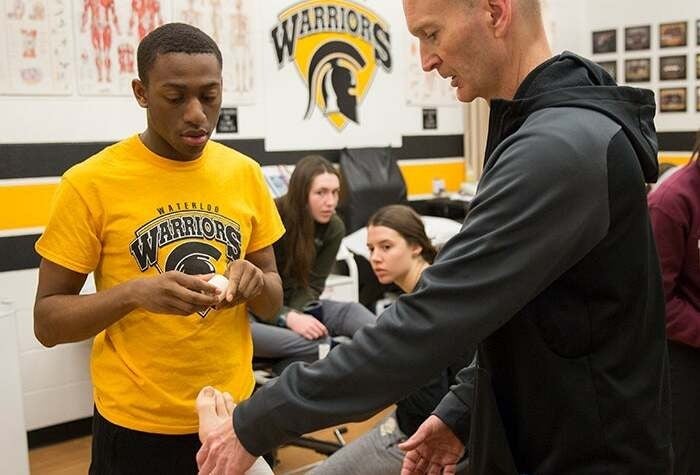 A Kinesiology student inspects an athlete's leg