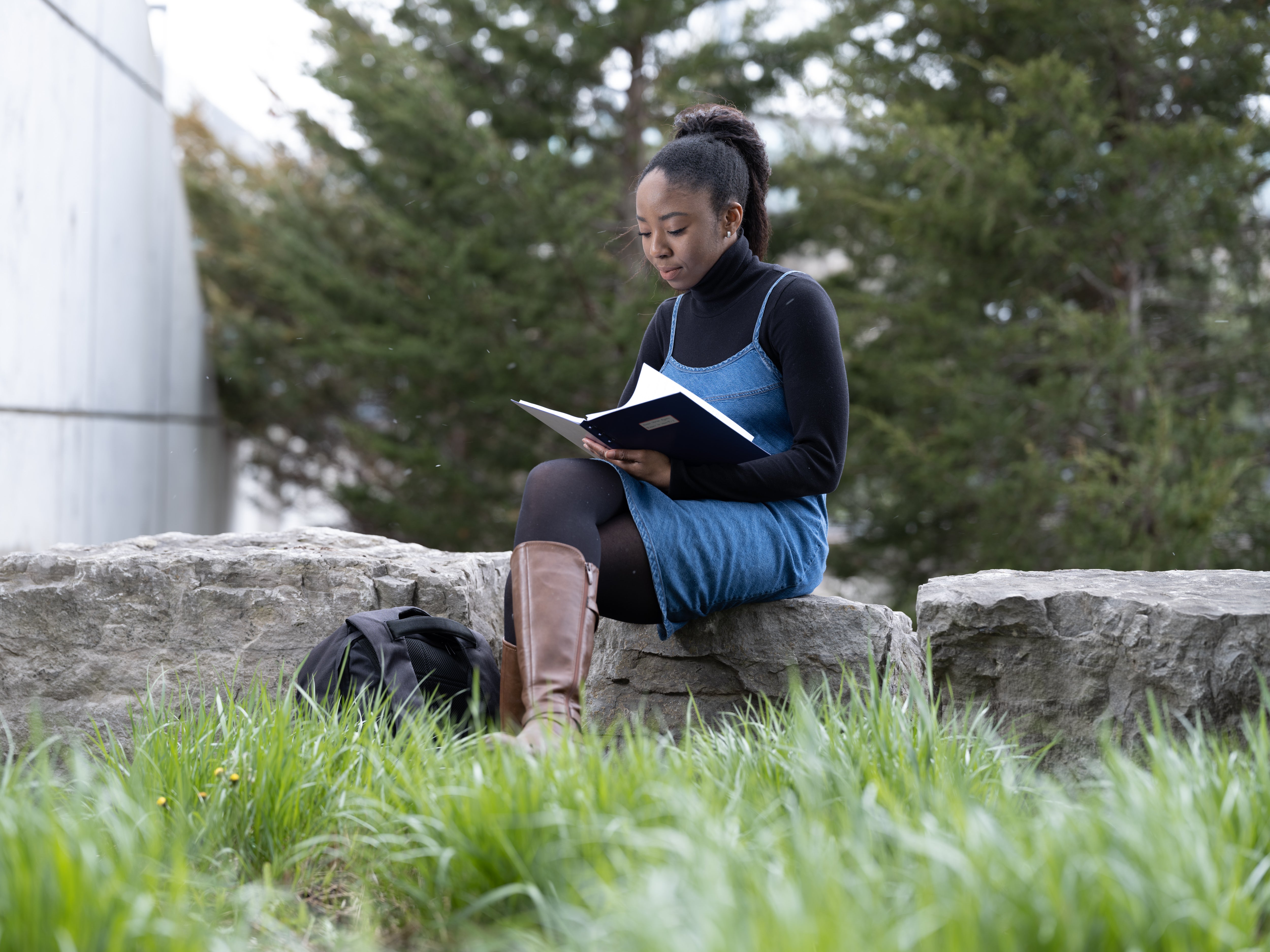 Student sitting on a log and reading a book