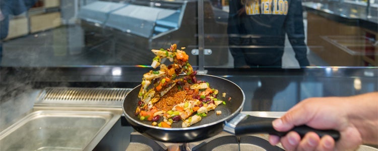 Food being tossed in a frying pan