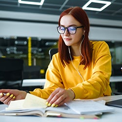 A woman studies from a book at a desk