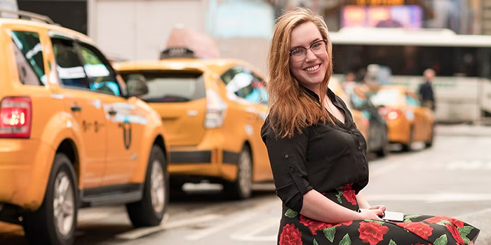 Hannah sitting outside and smiling next to a busy road.