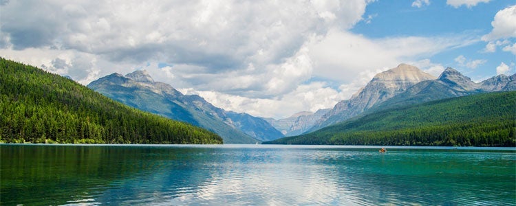 A lake with mountains behind it and forests on either side