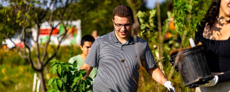 Ethan, a BSFM student planting a tree