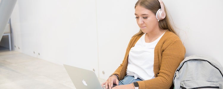 Student wearing headphones typing on laptop