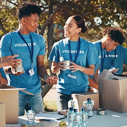 Two volunteers work at a table and smile at each other