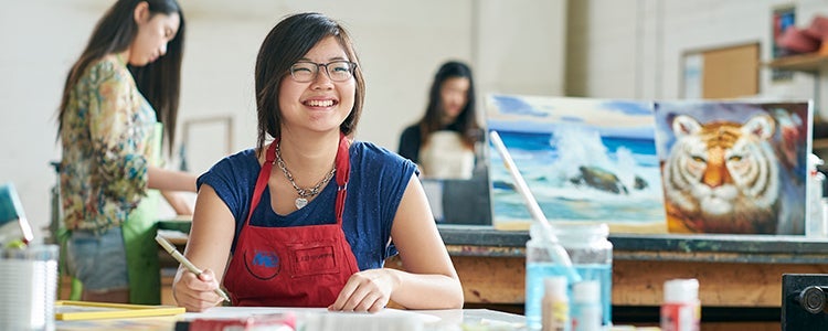 Student looking up while working in a bright art studio at the University of Waterloo