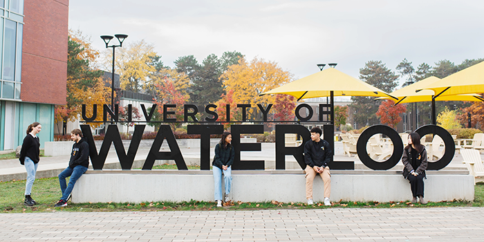 A group of students sitting on the Waterloo sign