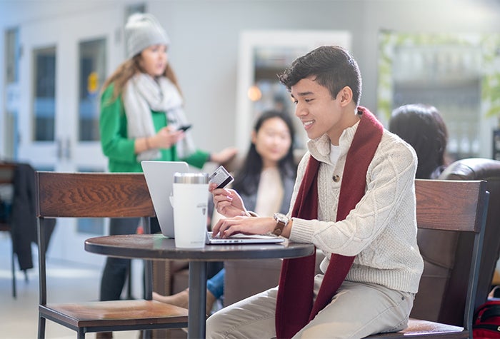 Student on a laptop with a credit card in their hand
