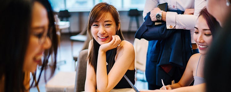 three students smiling around a table