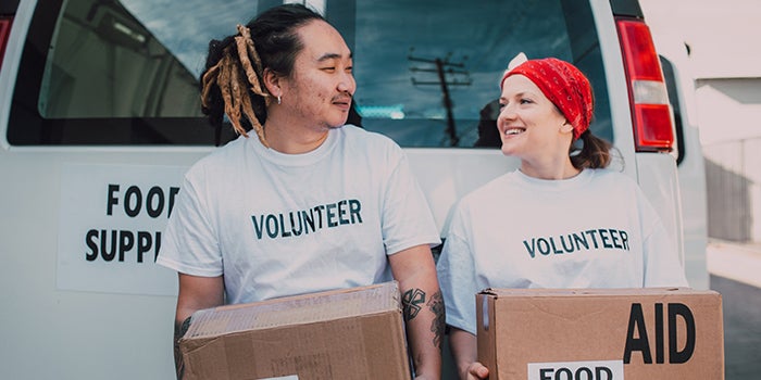 two students holding boxes and wearing shirts that say "volunteer" on them