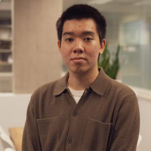 Hoang sits in an office while wearing a brown shirt