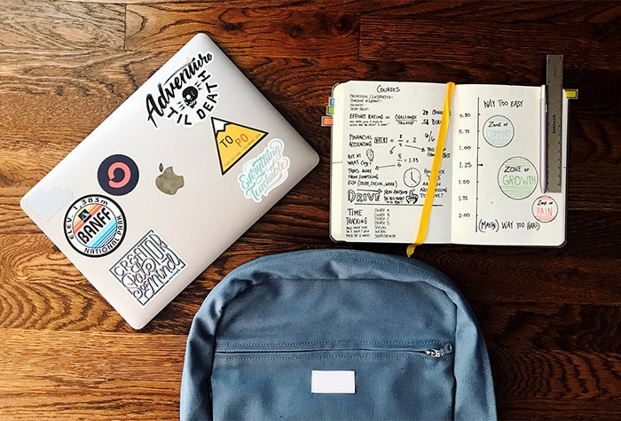 laptop, backpack and open notebook on table