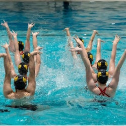 The Artistic Swimming team perform a routine in a pool