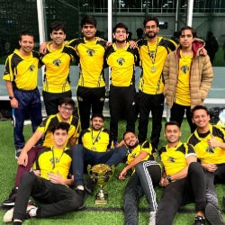 Members of the Cricket Club pose for a picture next to a trophy