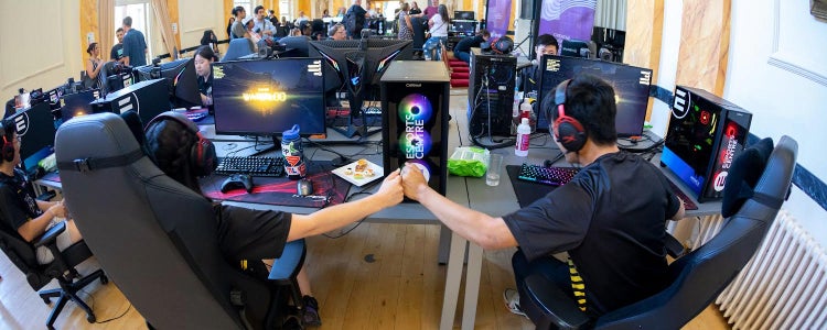 Students playing a video game fist bump each other