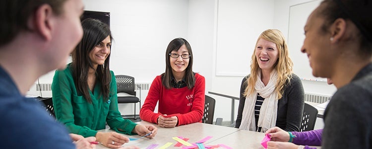 group of students looking at one student wearing red top at a classroom table