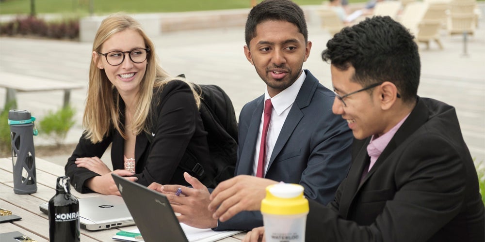 Students in a co-op program dressed in business attire at a table outside. 