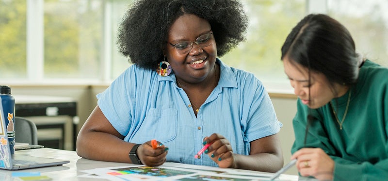 Two students working at a table in a bright studio at the University of Waterloo