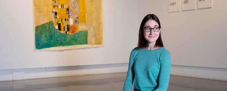 student standing in museum in front of art piece