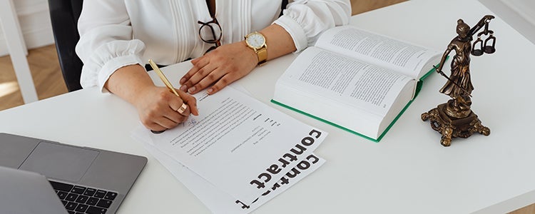  A student studying to become a lawyer working at their desk with books open in front of them.