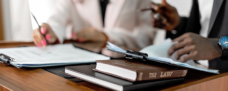  Two lawyers sitting at a desk together talking.