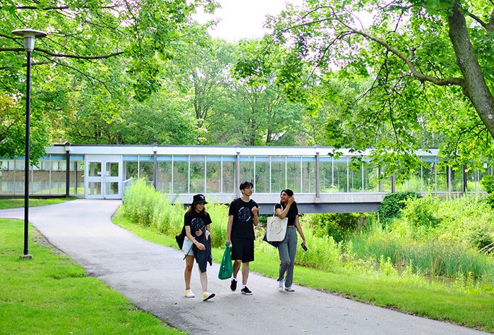 Three students walking on a trail on campus