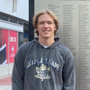 Luke smiles while wearing a hoodie outside