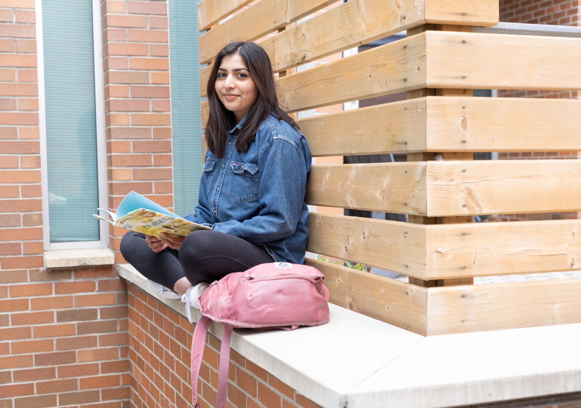 Manal sitting on a ledge outside.