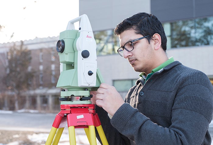 Student using surveying equipment mounted on a tripod