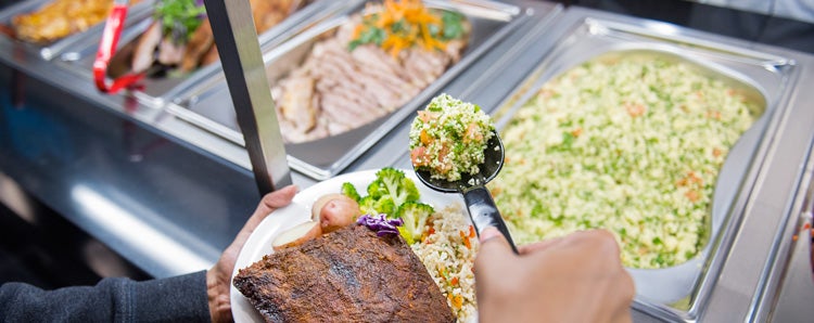 Taking a serving of food from a campus eatery