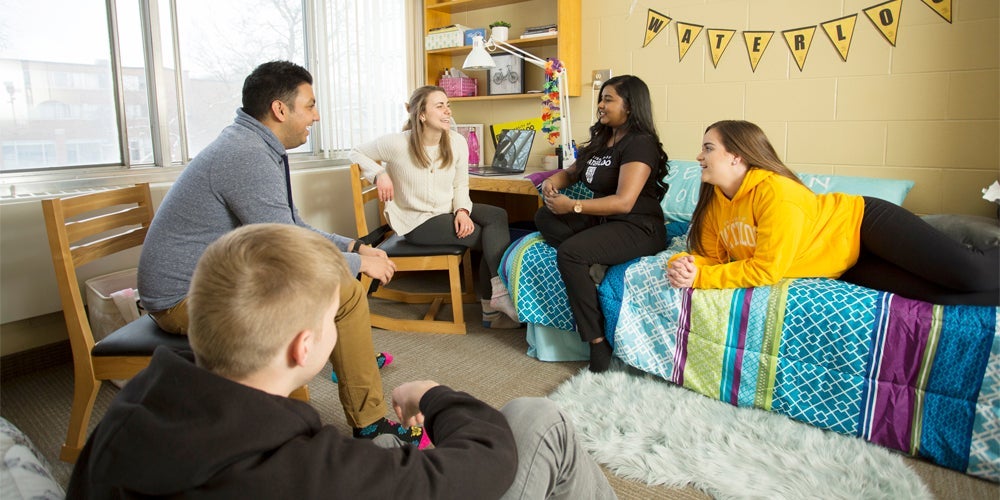 four students talking in a decorated residence room