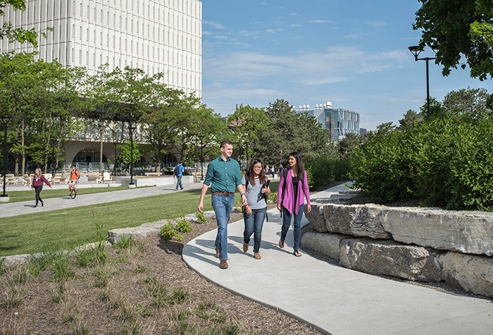 Three students walking on a path on Waterloo's campus.