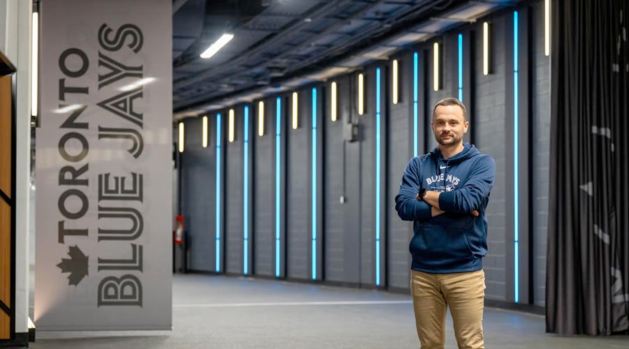 Waterloo graduate with a Toronto Blue Jays banner beside him