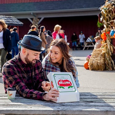 Two people sitting at a bench and eating the famous St. Jacobs fritters.