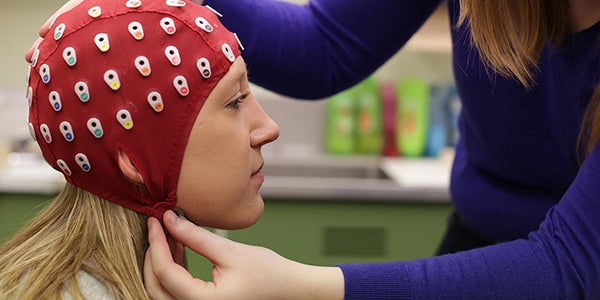 A Psychology student putting a brain activity monitor on another student's head