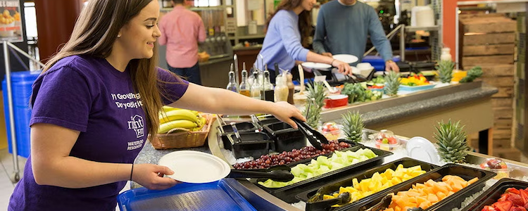 Student grabbing fruit at a residence eatery.