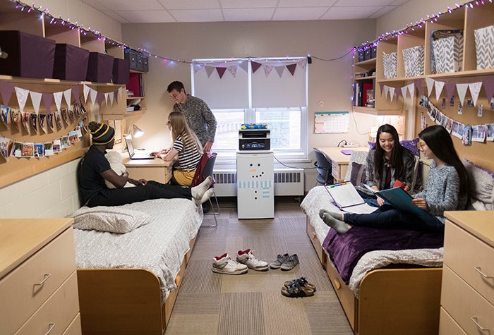 four students sitting and talking in their dorm 